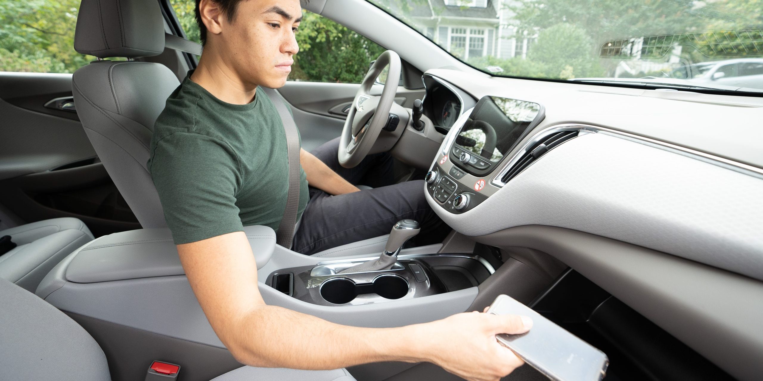 Teen placing phone in a glove compartment. Source: NHTSA Image Library.