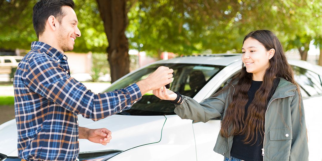 Adult handing teen car keys.